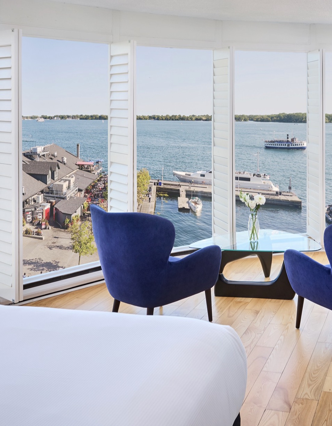 Bright guest room with floor-to-ceiling windows overlooking boats on Lake Ontario