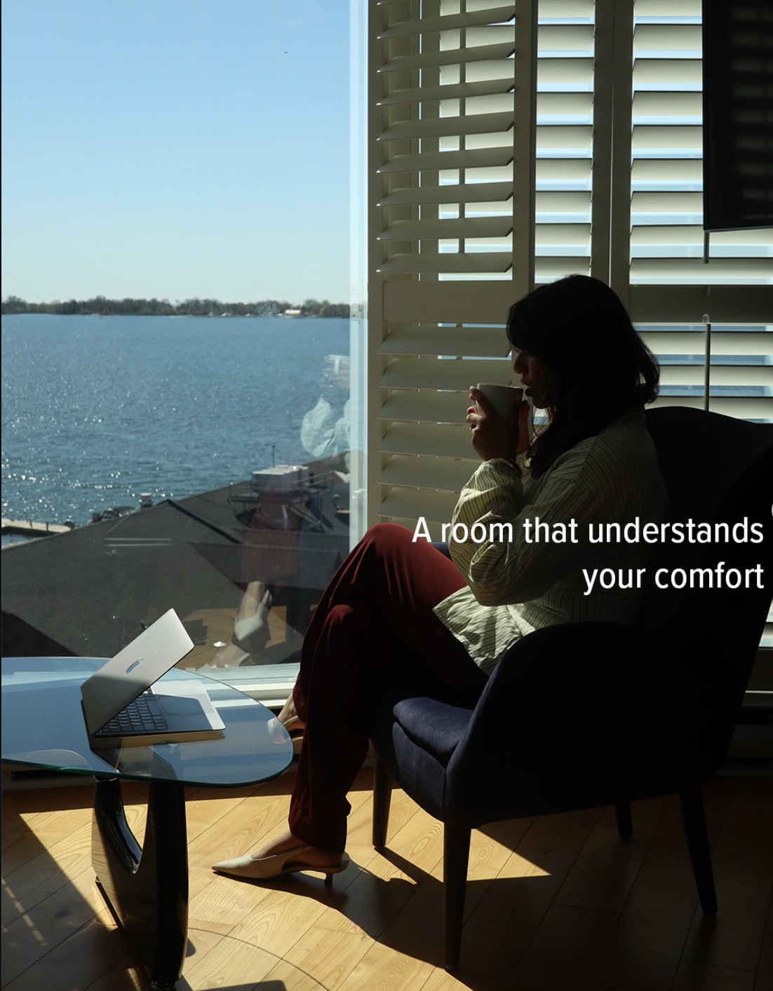 Guest enjoying coffee by the window of a harbourview room at sunrise